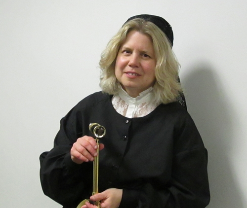 Noreen Grice dressed in costume as Maria Mitchell, holds a telescope