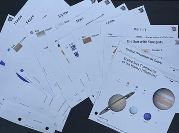 This photo shows all 16 tactile images from Touch the Solar System,arranged at different angles and on top of each other. Only one colorfultactile image on the top is completely visible; 
a size comparison of the planets.
